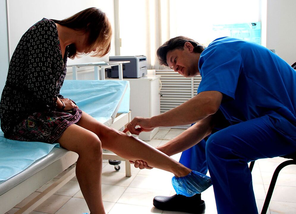 a doctor examines a leg with varicose veins